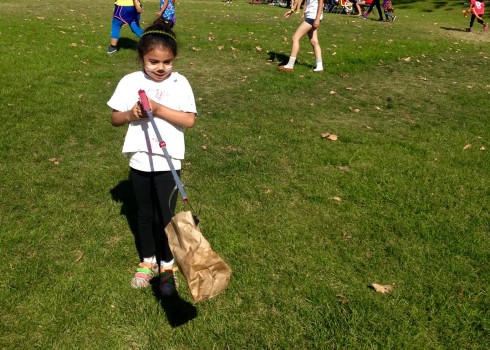 Girls Inc girl picking up trash with a smile on her face. -Travis